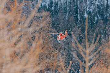 swiss Red helicopter flying over winter forest during rescue mission © Juanmarcos