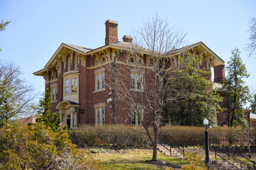 Wide view of a historic brick house with trees and clear sky © Viola