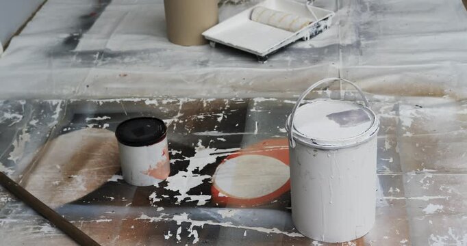 Paint bucket and roller sitting on cloth at doorway while camera pulling back revealing interior