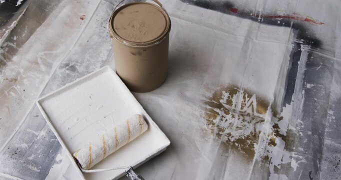 Paint can, tray, roller are resting while camera is panning, revealing stained drop cloth for prep