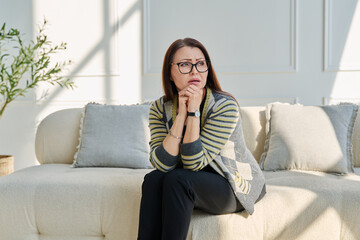 Obraz premium Mature sad woman experiencing stress, mental and physical pain, at home