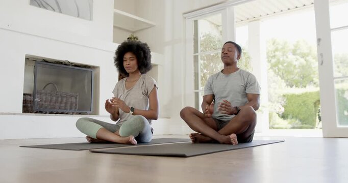 Guided meditation leading African American couple on mats moving prayer to mudra at home calming