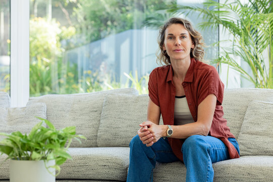 Woman sitting on sofa replying to cue, floating health icons around hands highlighting tips