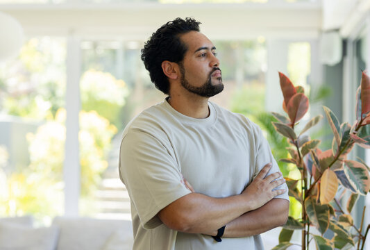 African American man folding arms in bright home near glass doors, potted plant, wristwatch