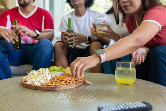 Diverse friends sitting on couch sharing snack platter, wearing casual clothes, copy space