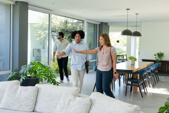 Home tour group touring modern open-plan living dining area in casual clothing holding tablet