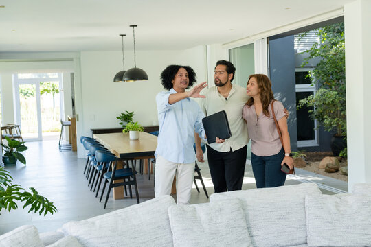 African American agent and couple viewing open-plan living area, holding portfolio and phone