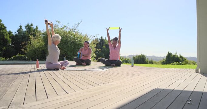 Diverse women on deck following silver leader lifting weight, using bands with water for mobility