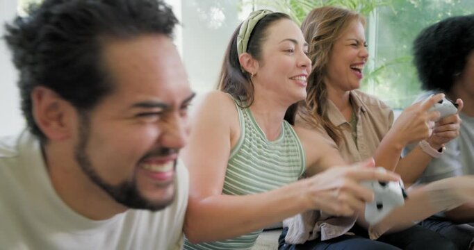 Diverse friends starting game on sofa beside glass wall, holding white controllers, playing to win