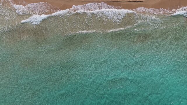 Aerial drone view of soft waves rolling onto golden sand at Fig Tree Bay, Protaras, Cyprus
