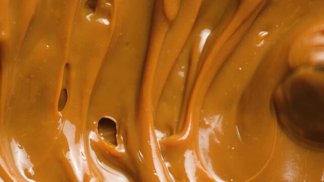 Dense caramel fudge texture being stirred. Dulce de leche thick boiled condensed milk.
