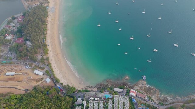 A luxury beach resort with many buildings and a swimming pool sits between a lush green forest and a sandy beach Nai Han Beach Viewpoint Phuket