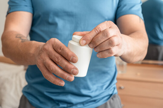 Man holding an unlabeled plastic bottle, offering supplements or medication for wellness and self-care
