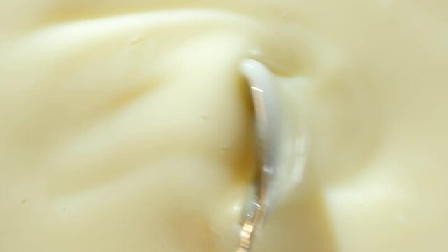 Spoon stirring condensed milk, condensed milk texture top macro view