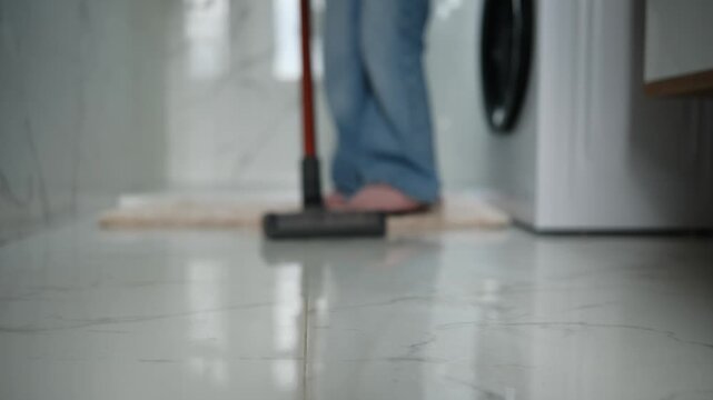 Close-Up Of A Woman Vacuuming The Bathroom Floor