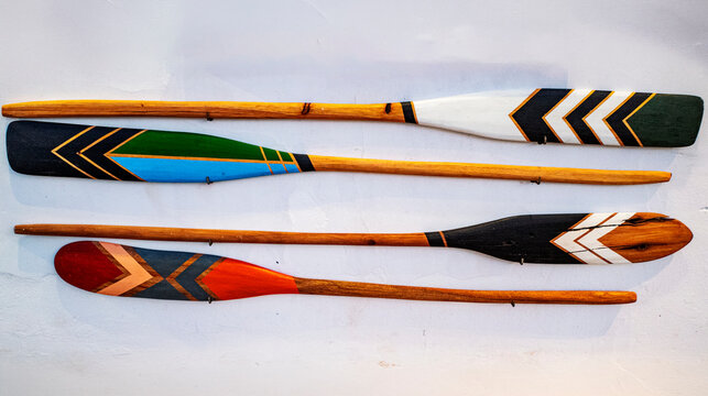 Wooden paddles used in canoes, decorated with traditional indigenous designs, sold as decorative items. Barra Grande, Bahia, Brazil. 2024 