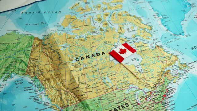 Hand adjusts Canada flag on detailed northern territory map