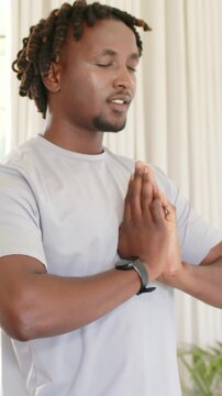 Vertical video: Bringing hands together man meditating at home, holding prayer pose with wristwatch