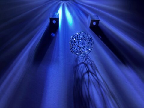 Wire sphere with wooden cubes on blue abstract background with light rays