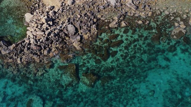 Aerial drone view of a quiet Konnos Beach rocky bay with crystal clear turquoise water in Cyprus