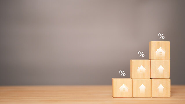 Real estate investment concept with wooden blocks, house icons and percentage symbols representing mortgage rates, financial growth and property market trends in a clean minimal background with copy s