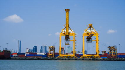Obraz premium Industrial cargo container terminal with large orange gantry cranes loading shipping containers at seaport, logistics import export, global trade transportation and freight operations concept