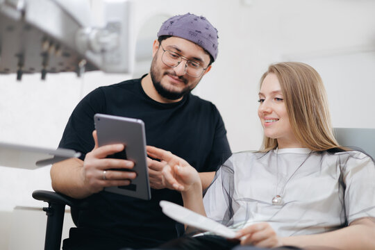 Young caucasian female at dental appointment with male dentist discussing treatment options, consultation in stomatology clinic