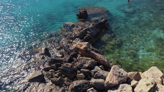 Aerial drone view of a quiet Konnos Beach rocky bay with crystal clear turquoise water in Cyprus