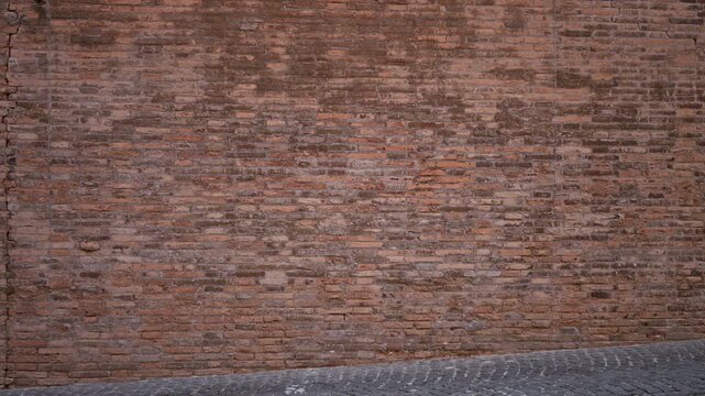 Weathered red brick wall texture in sharp detail along a cobbled street; backplate copyspace background template.