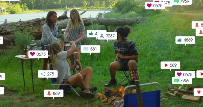 Pouring drinks four friends gathering at river edge, with table, campfire, notifications appearing