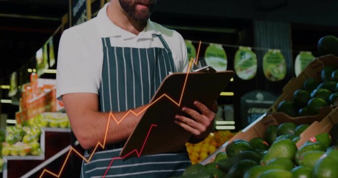 Camera pulling back, produce clerk inspecting avocados, noting stock while line charts crossing pad