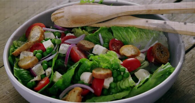 Camera moving closer, salad bowl revealing lettuce and tomato, spoons resting highlighting texture