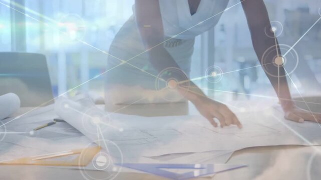 Fashion designer leaning and spreading patterns at studio, animated node overlay mapping layout