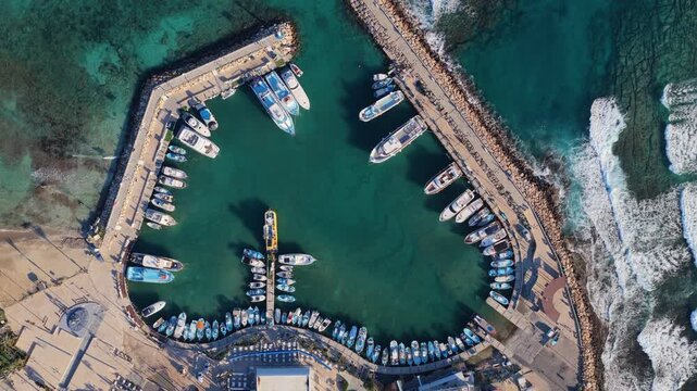 Aerial drone view of marina in Ayia Napa, Cyprus, with boats arranged symmetrically inside protected harbor waters