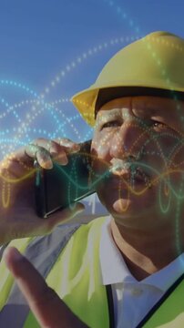 Vertical video: Site pro raising radio to ear after call, checking time while waves overlaying face