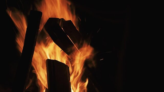 Flackerndes Lagerfeuer in Nahaufnahme vor dunklem Hintergrund, warme Flammen und ruhige Nachtstimmung