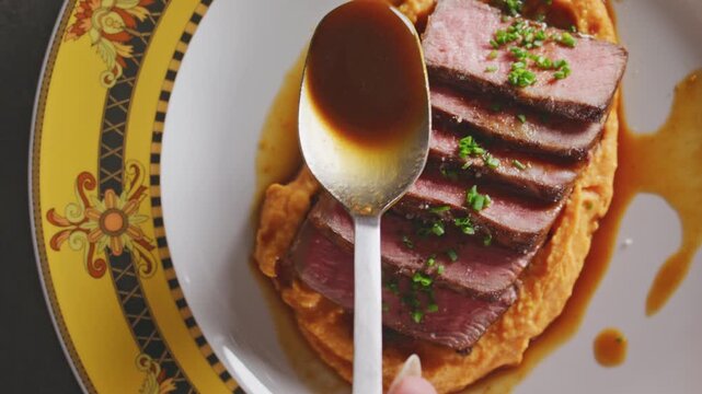 Seared NY strip steak slices on sweet potato pur�e, drizzled with sauce and garnished with herbs.