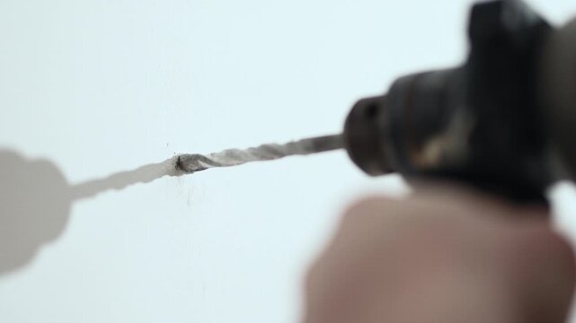 Close up of man drilling hole in wall with electric drill for shelf installation, 10-bit 4K.