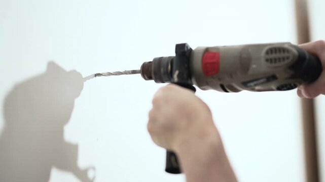 : Close up of man drilling hole in wall with electric drill for shelf installation, 10-bit 4K.