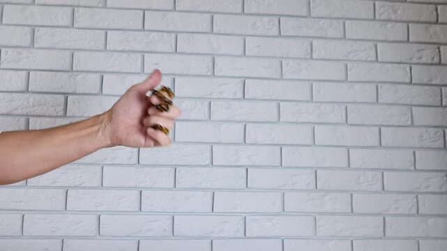 Male hand playing with worry beads. Closeup of a man's hand nervously fidgeting and twirling a set of brown amber worry beads, also known as komboloi, ending with a thumbs-up gesture