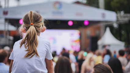 Little girl enjoying outdoor music festival, sitting on shoulders in a large crowd © Довидович Михаил