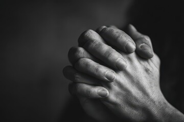 Fototapeta premium Close-up of hands in prayer in black-and-white, an intimate study of quiet devotion