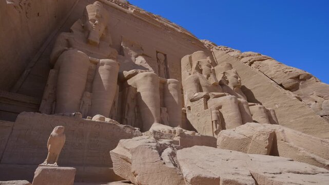 Close-up of giant Ramesses II colossi carved into rock facade at Abu Simbel temple, Egypt. Dramatic upward view of ancient sandstone pharaoh statues. Travel and history.