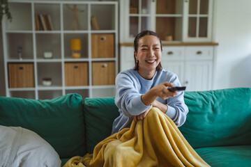 Obraz premium Woman relaxing at home watching television with remote control