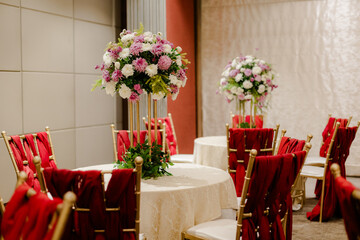 Elegant Reception Decor with Floral Centerpieces and Red Velour Chairs, Perfect for Weddings,...