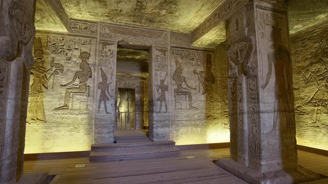 Atmospheric interior of Small Temple of Nefertari at Abu Simbel with carved gods reliefs, hieroglyphics and warm golden lighting, Egypt. Rare inside view for history content.