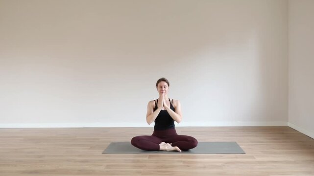 A young woman practicing yoga in a bright modern studio, focusing on balance, breathing, and mindfulness.