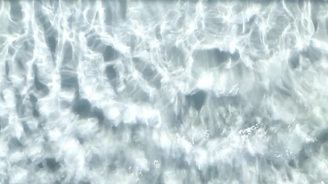Abstract close-up of clear sunlit water with moving ripple patterns across the surface, flowing continuously from frame to frame and forming bright textured waves for a calm background.