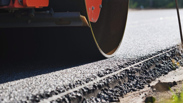 Road roller compacting fresh asphalt during new highway construction