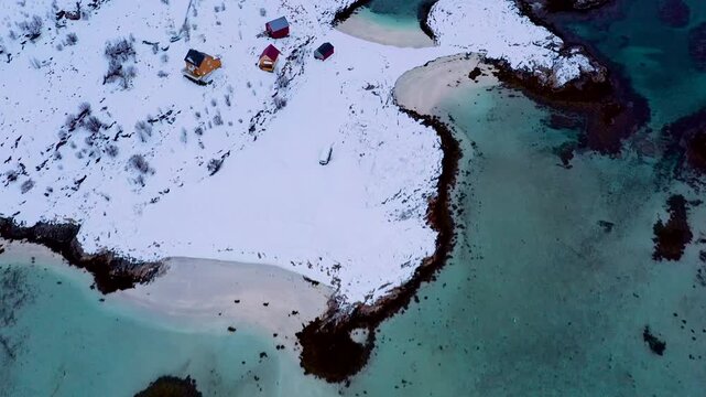 Top-Down Drohnenflug &uuml;ber schneebedeckte arktische Inseln mit t&uuml;rkisfarbenem Wasser in Bewegung, Nordnorwegen 4K